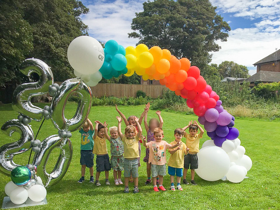 Last day pupils under rainbow balloon arch